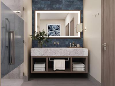 Baño moderno con espejo iluminado, lavabo y toallas debajo del tocador.