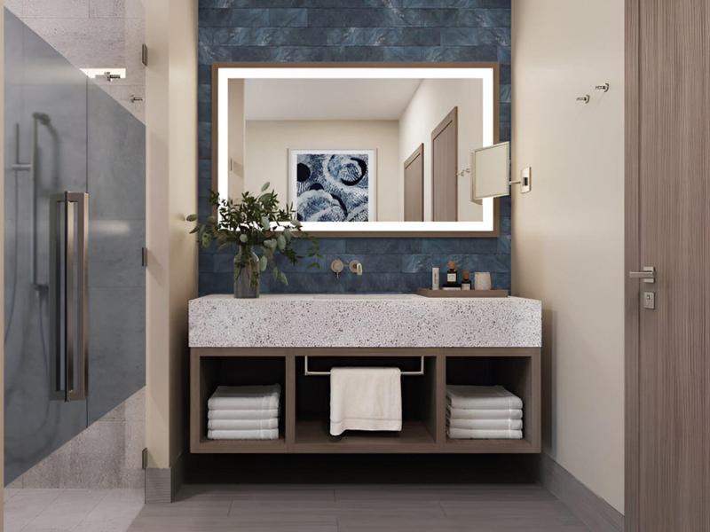 Baño moderno con espejo iluminado, lavabo y toallas debajo del tocador.