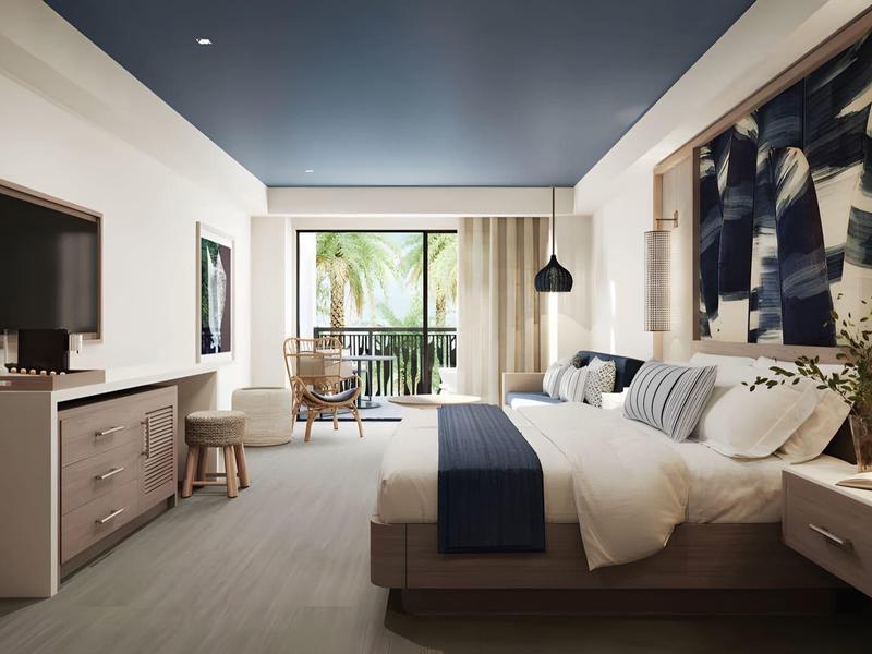 Habitación de hotel moderna con cama doble, TV, balcón y decoración elegante.