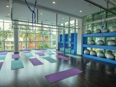 Großer heller Fitnessraum mit Yogamatten, blauen Regalen und Gymnastikbällen vor Fensterfront.