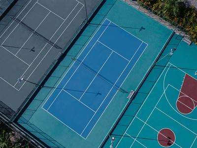 Drei nebeneinander liegende Sportplätze mit Tennis- und Basketballfeldern in unterschiedlichen Farben.