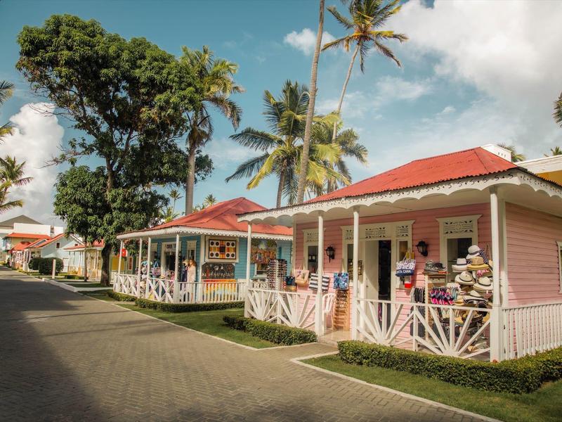Kolorowe drewniane domki z zadaszonymi werandami na tropikalnym terenie hotelu w słoneczny dzień.