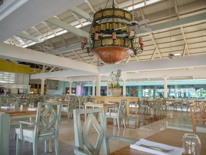 Jasna, przestronna restauracja hotelowa z białymi krzesłami i dużym żyrandolem.