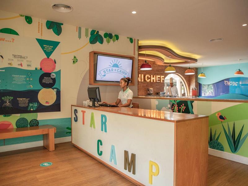 Recepcja hotelowa z ladą i kolorowymi dekoracjami ściennymi.