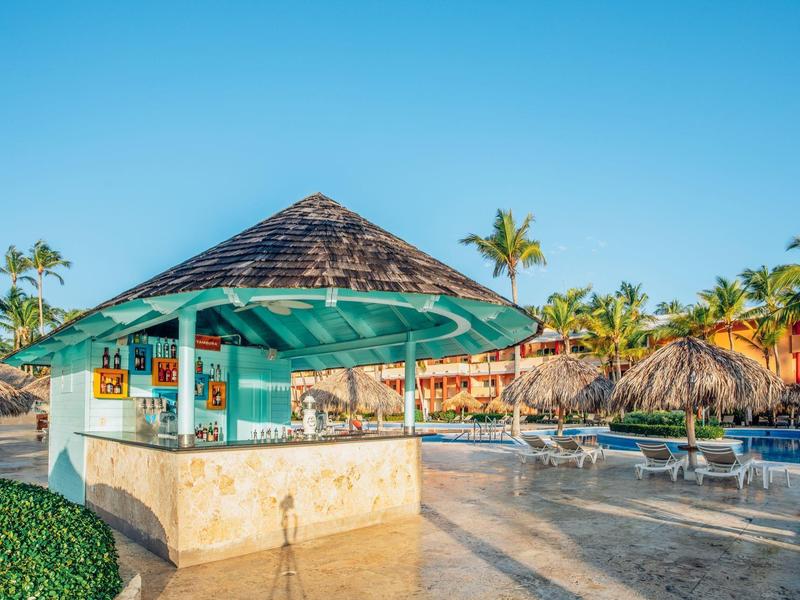 Mały bar z dachem ze strzechy przy słonecznym basenie w ośrodku wakacyjnym.