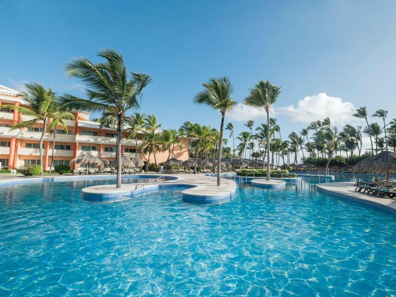 Hotelowy basen z palmami i leżakami w słoneczny dzień.