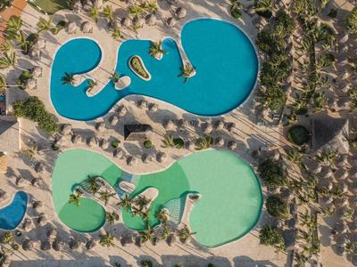 Widok z lotu ptaka na duży hotelowy basen z osobną częścią dla dzieci w tropikalnym otoczeniu.