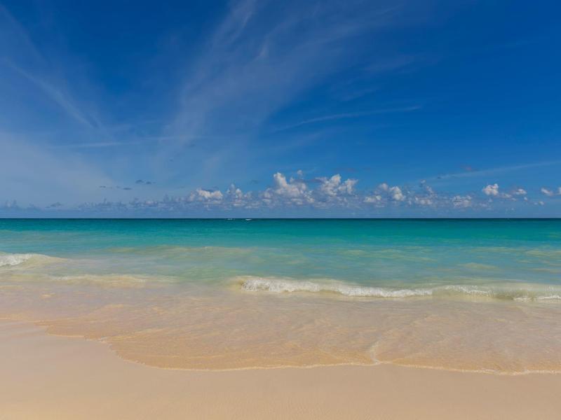 Clear turquoise sea with gentle waves and blue sky at the sandy beach.