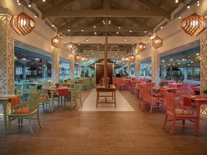 Large open dining area with colorful chairs and lantern lighting in a hotel.