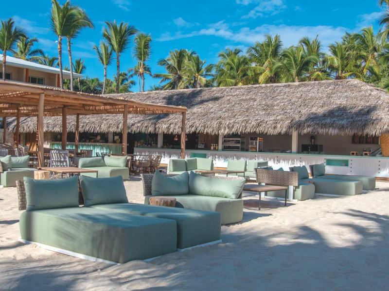 Beach bar with lounge furniture and palm trees under a blue sky