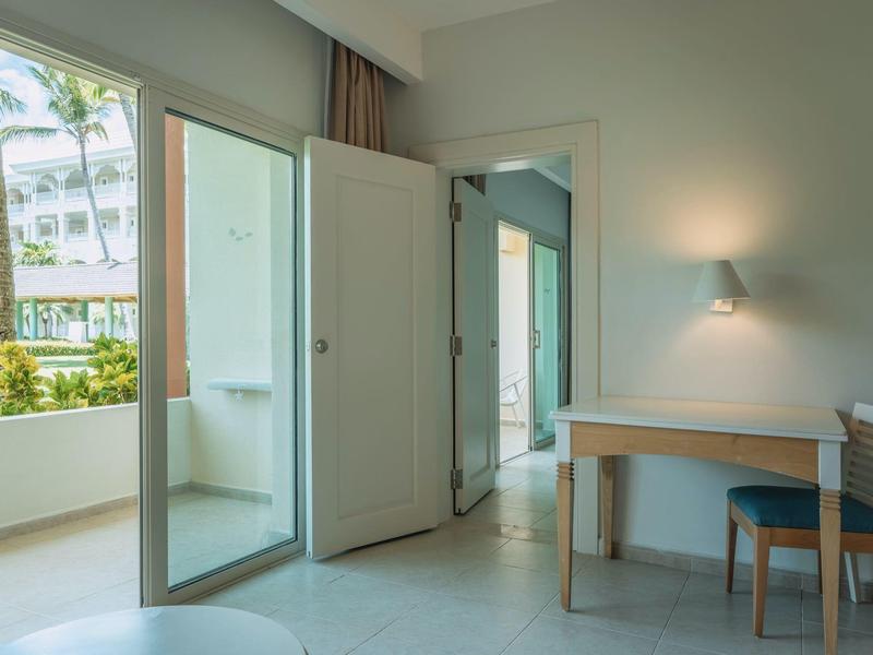 Bright hotel room with open balcony and desk with chair against the wall