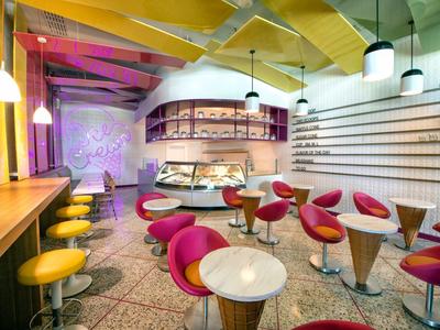 Modernes Café mit bunten Sitzmöbeln, runden Tischen und hellem, ansprechendem Interieur.