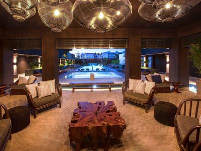 Elegantes Wohnzimmer mit Holzvertäfelung, großen Lampen und Blick auf beleuchteten Pool.