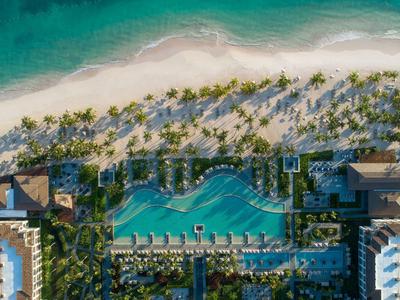 Luftaufnahme eines Resorts mit großem Pool, weißen Sandstrand und türkisfarbenem Meer.