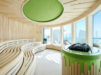 Helle Sauna mit gebogenen Holzliegen und großen Panoramafenstern mit Blick auf die Stadt.