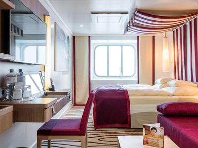 Modern eingerichtetes Hotelzimmer mit Doppelbett, Schreibtisch und Sitzbereich nahe einem Fenster.