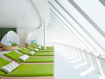 Moderne Entspannungslounge mit grünen Liegen und Tagesbetten unter schrägen Fenstern