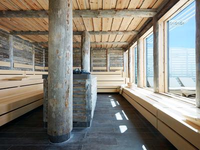 Moderne Sauna mit Holzverkleidung und großen Fenstern, die Tageslicht hereinlassen.