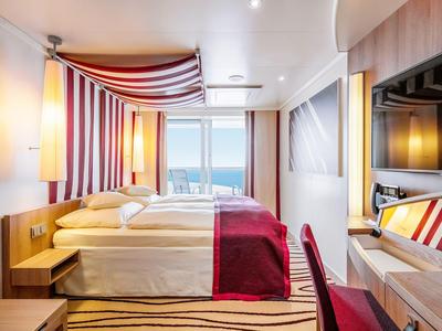 Modernes Hotelzimmer mit zwei Einzelbetten, roten Akzenten und Meerblick durch das Fenster.