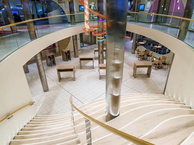 Elegante, geschwungene Treppe mit moderner Beleuchtung in einem Hotelinneren.