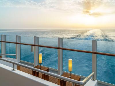 Balkon mit Glasgeländer und Meerblick bei Sonnenuntergang auf einem Kreuzfahrtschiff