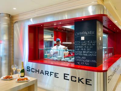 Modernes Burger-Restaurant mit rotem Fensterrahmen und digitalem Menü in hell erleuchtetem Innenraum.