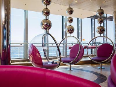 Moderner Lounge-Bereich mit hängenden Glaskugelsesseln und Meerblick durch große Fenster.