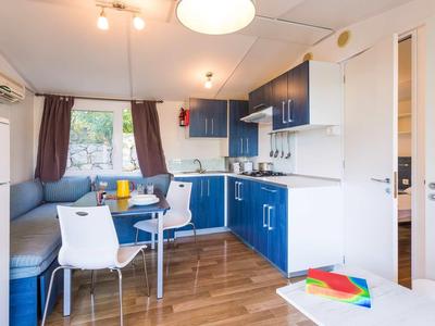 Kompaktowa nowoczesna kuchnia z niebiesko-białymi szafkami i jadalnią w hotelu lub domu wakacyjnym.