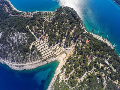 Widok z lotu ptaka na zalesiony półwysep z przystaniami i plażami nad morzem.