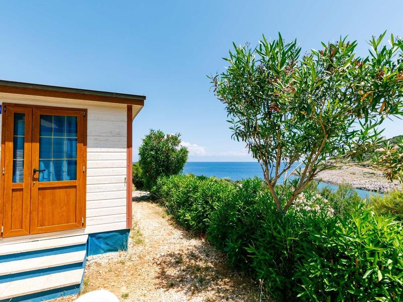 Wejście do domu wakacyjnego z widokiem na morze i zieloną roślinnością pod czystym niebem.