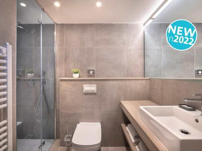 Modernes Badezimmer mit Dusche, WC und Waschbecken in neutralen Farbtönen.