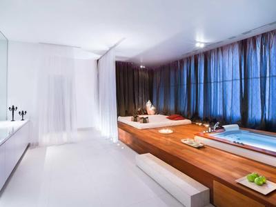 Schlichte, moderne Wellness-Oase mit Whirlpool, dunklen Vorhängen und weißen Wänden