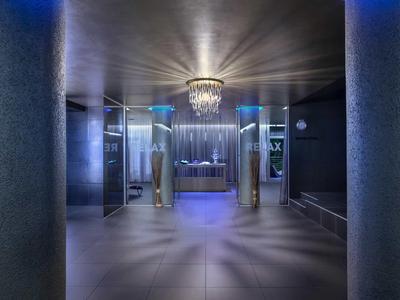 Moderner Eingangsbereich mit silbernen Säulen, blauem Licht und funkelndem Kronleuchter.