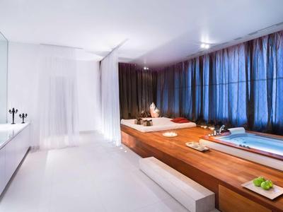 Moderner Wellnessraum mit weißen Wänden, Holzwanne, blauen Vorhängen und minimalistischem Dekor.