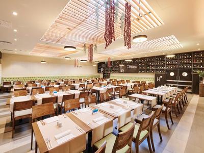 Modernes Restaurant mit Holzstühlen, langen Tischen und schattierten Deckenlampen.