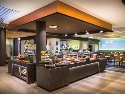 Moderner und großzügiger Buffetbereich mit vielen Speisen auf dunklen Theken in hellem Raum.