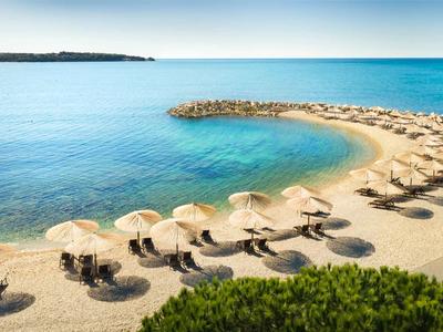 Strand mit Reihen von Liegestühlen und Sonnenschirmen am klaren, ruhigen Meer.