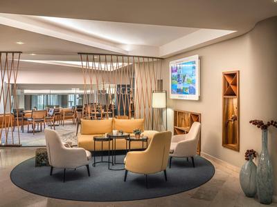 Modern eingerichteter Lounge-Bereich mit bequemen Sesseln und Sofas in warmem Licht.