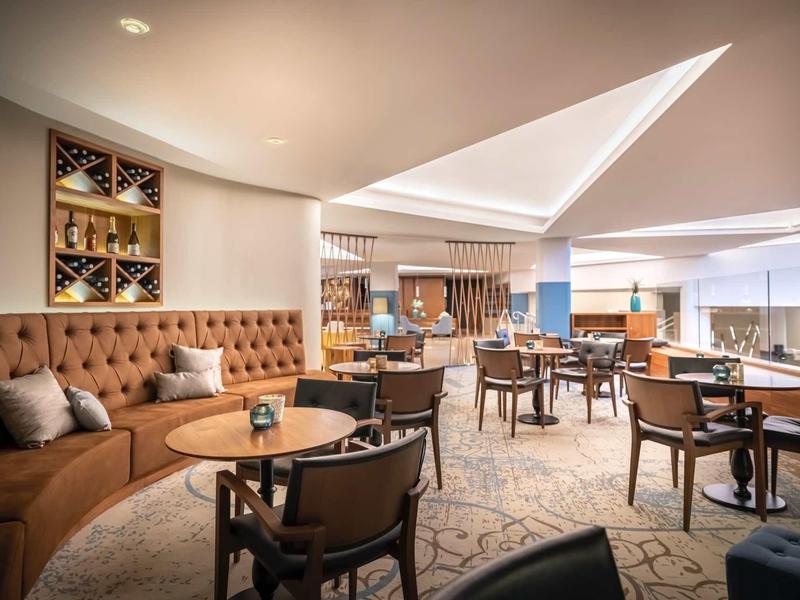 Moderner, gemütlicher Sitzbereich mit braunen Polstermöbeln, Holztischen und weichem Teppich.