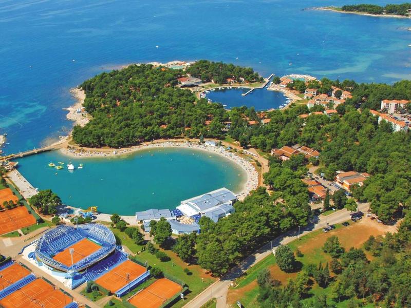 Widok z lotu ptaka na nadmorski ośrodek z kortami tenisowymi, lasami i zatokami