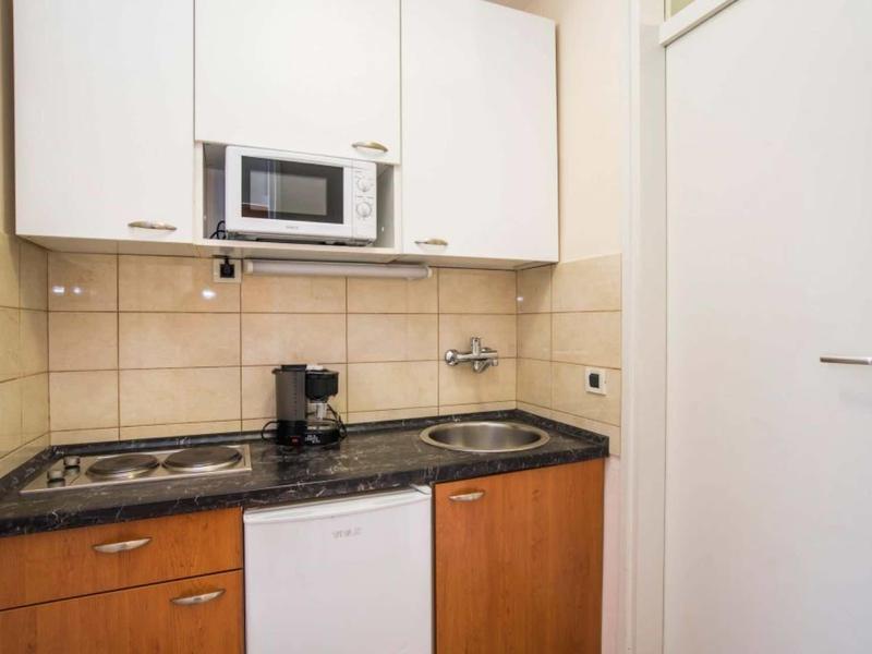 Mała aneks kuchenny z kuchenką, ekspresem do kawy, mikrofalówką i zlewem w niewielkiej przestrzeni.