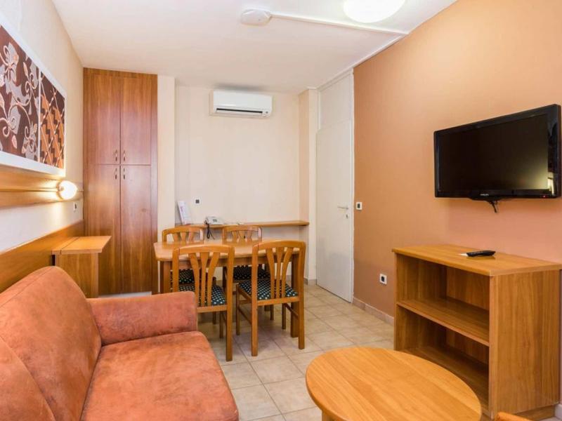 Przytulny salon z kanapą, stołem jadalnym, telewizorem i drewnianą okładziną w ciepłych kolorach.