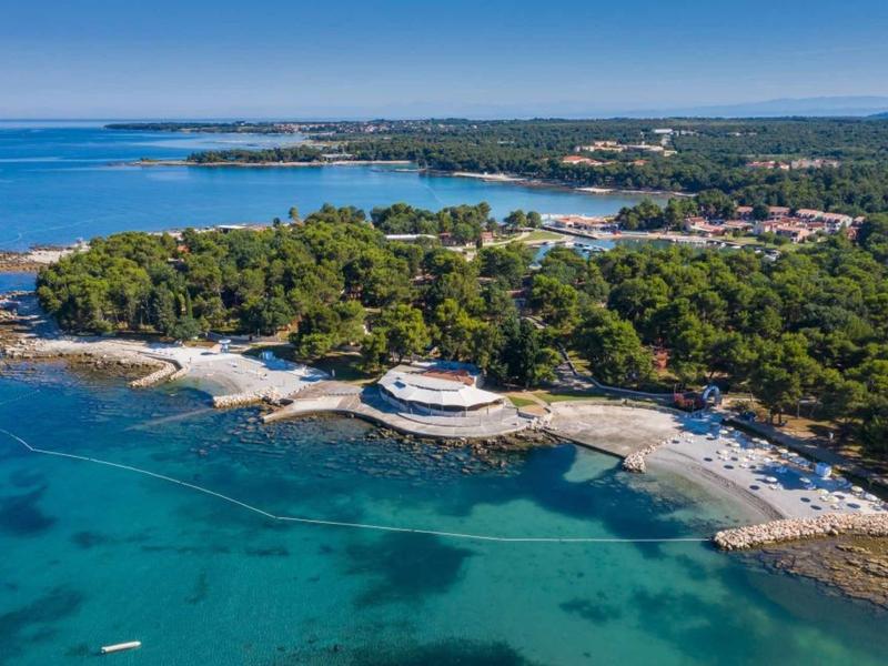 Wybrzeże z czystą wodą, plażą i zalesionym terenem z okrągłym budynkiem nad brzegiem.