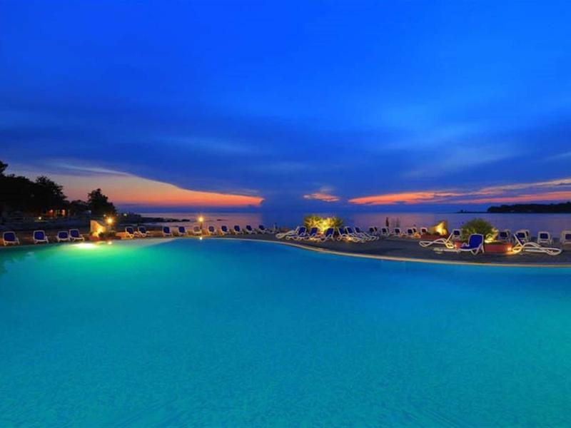 Duży oświetlony basen z miejscami do siedzenia o zachodzie słońca pod czystym niebem.