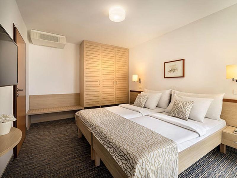 Modernes Schlafzimmer mit Doppelbett, Holzmöbeln, Teppichboden und minimalistischer Dekoration.