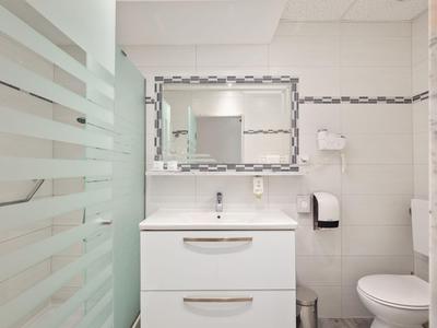 Heller, moderner Hotelbadezimmer mit Waschbecken, Spiegel und Toilette.