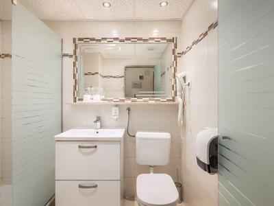 Kleines Badezimmer mit weißem WC, Waschbeckenunterschrank und rechteckigem Spiegel.