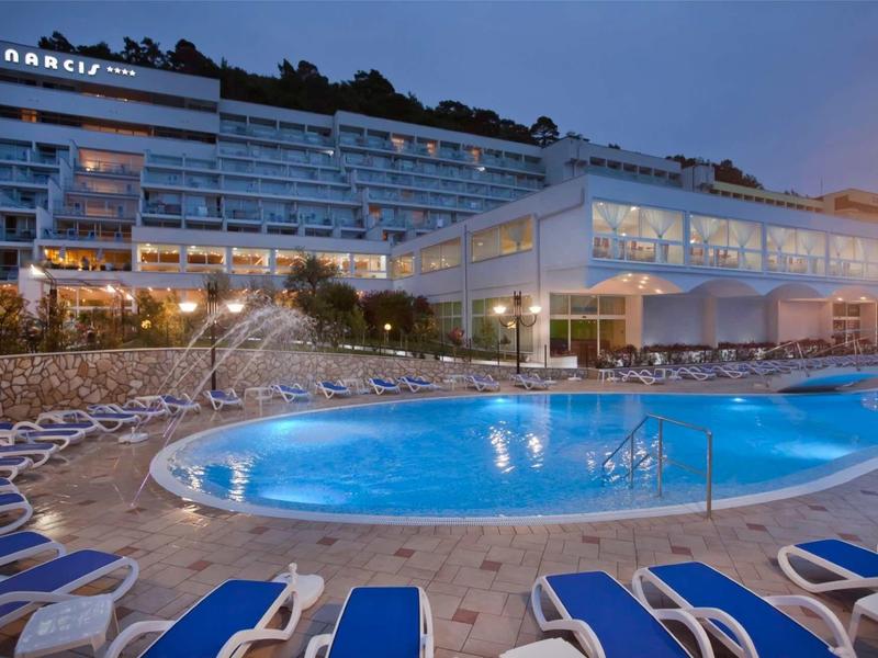 Evening view of Danubius hotel with illuminated pool and sun loungers.