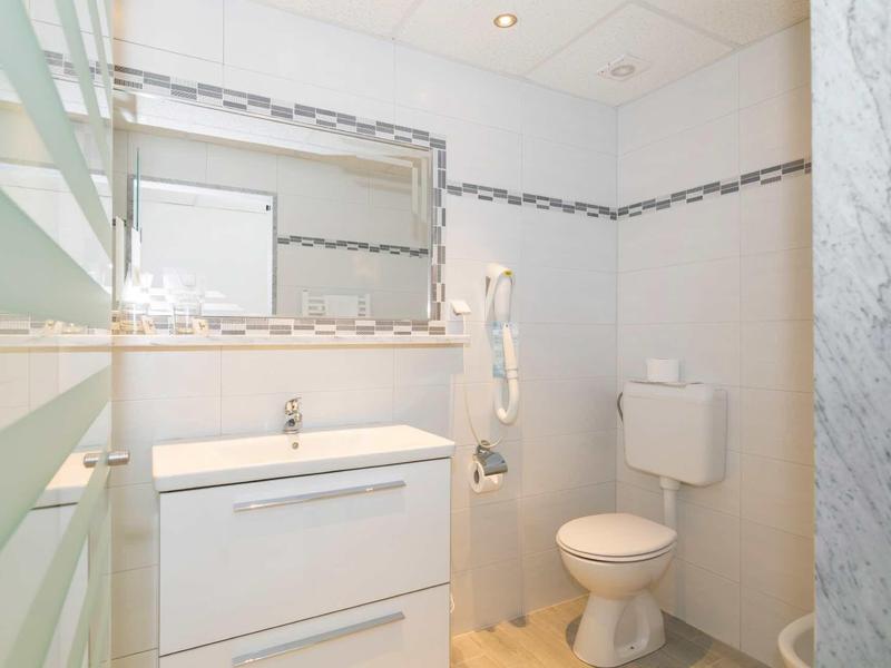 Bright bathroom with shower, toilet, sink, and hairdryer in a simple design.