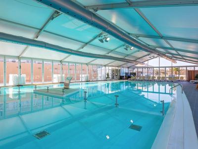 Piscina coperta con acqua limpida e grandi finestre in un hotel moderno.